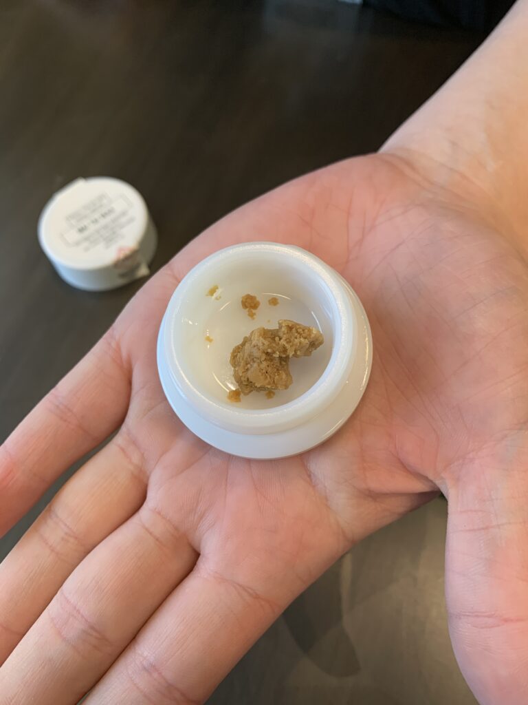 Marijuana concentrate in a ceramic container in a persons hand.